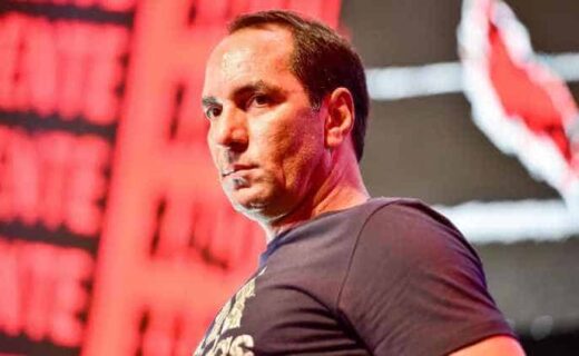 Homem com expressão séria, fundo vermelho vibrante.