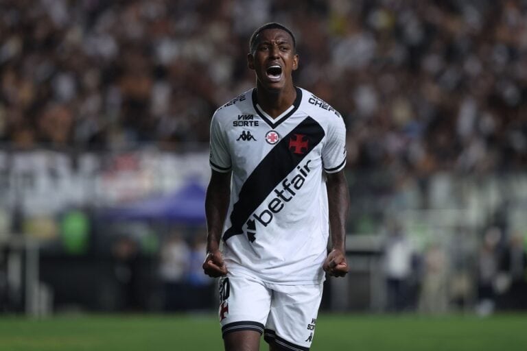2. Alt: Jogador do Vasco em uniforme branco e preto comemorando gol.