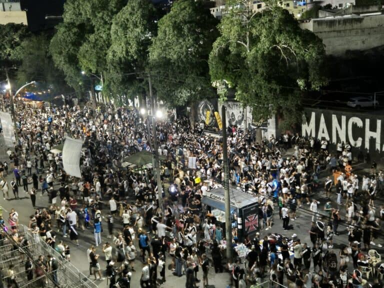 Torcida do Vasco reunida em rua, com muitas pessoas usando camisas e bandeiras do time.