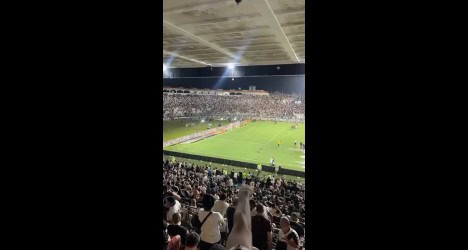 Vista aérea do estádio lotado, torcida vibrando, campo em destaque, ambiente animado e energia de um jogo emocionante do Vasco.