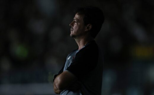 Homem observando, perfil em foco, estádio ao fundo.