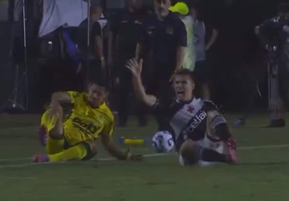 20251202-211502-1-6-lucas-piton-do-vasco-machuca-o-joelho-na-partida-contra-o-mirassol-foto-reproducao-sportv-1 2. ALT: Jogadores do Vasco e adversário na partida, com um deles caído no campo, em ação intensa durante o jogo.