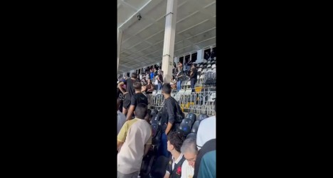 Torcedores do Vasco em partida no estádio, com torcida animada e assentos ao fundo, demonstrando entusiasmo eapreço pelo clube.