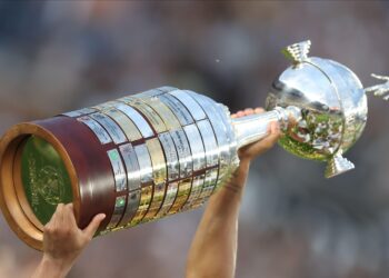 Troféu da Copa Libertadores sendo elevado por duas mãos.
