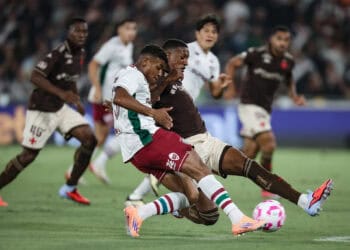 Jogadores do Vasco e adversário disputando a bola em campo.