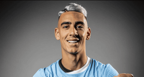 Jogador do Vasco sorrindo com uniforme azul.