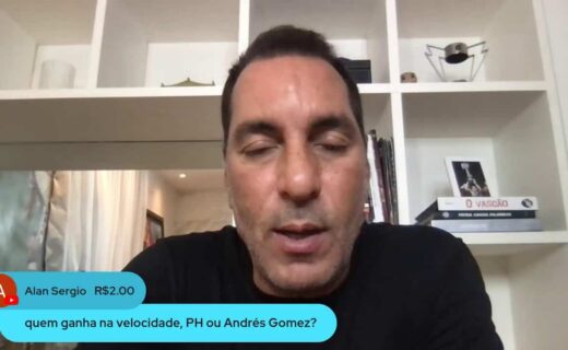 Homem falando em vídeo, fundo com estante e livros.